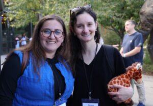 Two participants at an annual scientific meeting tour Cheyenne Mountain Zoo as part of the event. One woman holds a stuffed giraffe.