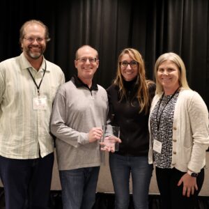 Three officers from national society present speaker award to fourth individual.