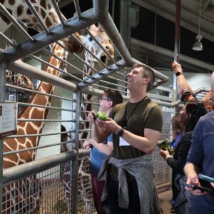 Research feeds a giraffe during a special activity while attending a national scientific meeting.