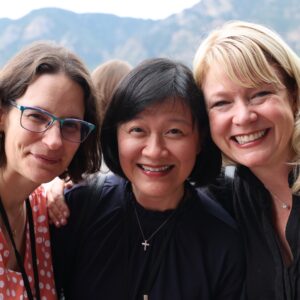 three members posing with mountains in the background