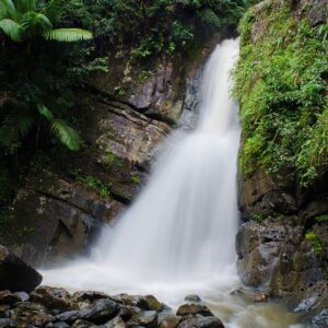 misty waterfall next to rock cliff and natural greenery