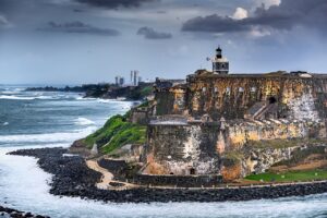 foamy ocean waves hitting the coast of the island with old architecture and a light house